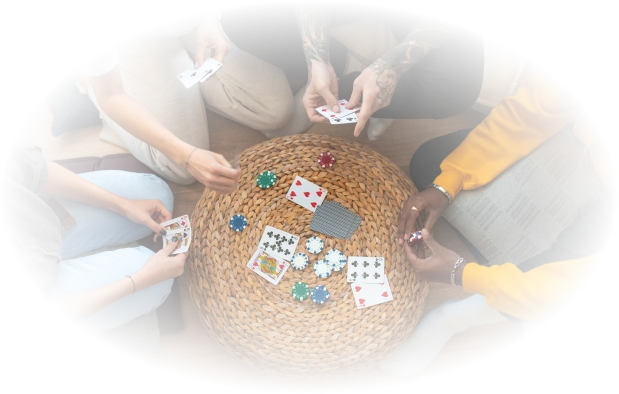 Vier mensen spelen kaart aan een ronde rieten tafel, omringd door pokerchips. De sfeer is informeel, met een gevoel van kameraadschap en ontspanning.